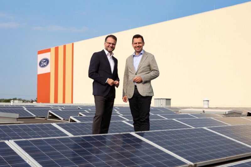 Zwei Männer auf einem Industriedach zwischen PV-Modulen.