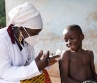 Zu sehen ist eine Krankenschwester in Afrika, die einem kleinen Jungen eine Spritze gibt. SophiA will solare Containerlösungen für Krankenhäuser in Afrika entwickeln.