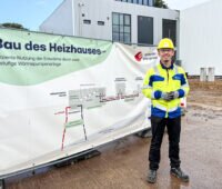 Der Projektleiter der Hamburger Energiewerke steht und signalgelber Arbeitskleidung vor dem neuen Heizhaus.