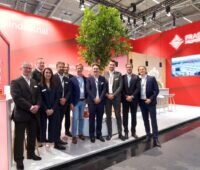 10 Personen in Business-Outfit auf einer Bühne in einer Halle mit Präsentation und dem Schriftzug Frasers.