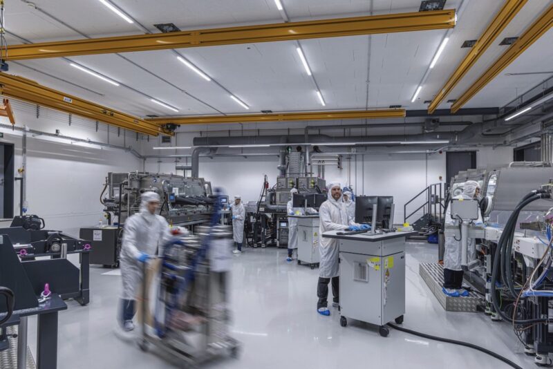 Blick in einem Raum des Fraunhofer ISE mit einigen kleinen Maschinen und Menschen, die sie bedienen. Hier finden praxisnahe Studien für die PV-Produktion statt.