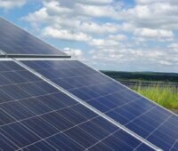 Bildanschnitt einer Freiflächensolaranlage in landwirtschaftlicher Umgebung.