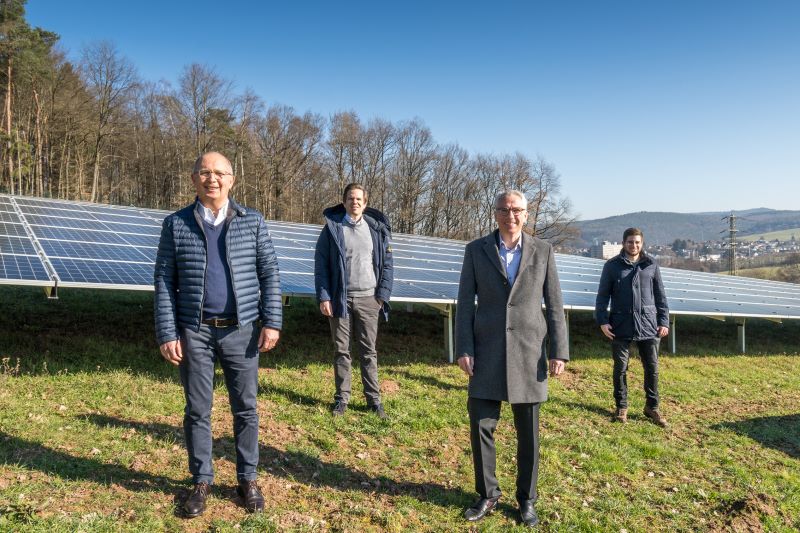 Vier Personen auf grüner hügeliger Wiese mit Photovoltaik .