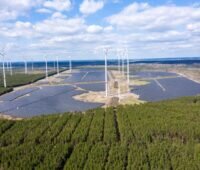 Bild eines Solarparks mit Windenergie, umrahmt von Bäumen