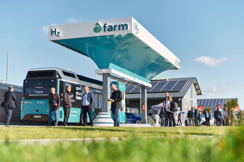 Wasserstofftankstelle mit Wasserstoffbus, Personen und PV im Hintergrund