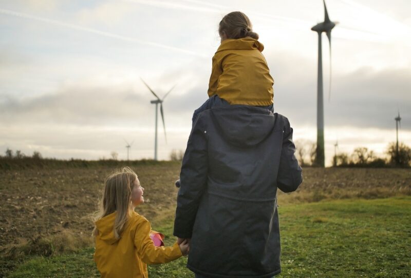 Zu sehen ist eine Person mit zwei Kindern vor einem Windpark als Symbol für GP Joule Invest Crowd.