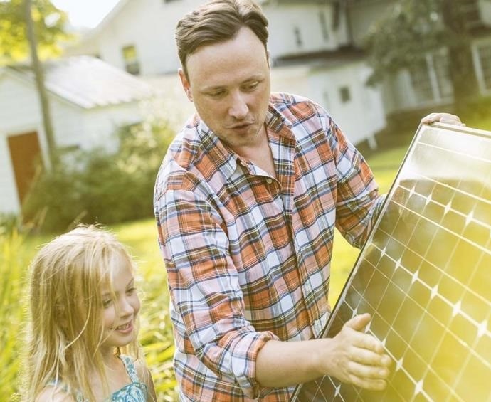 Im Bild ein Mann mit Kind und PV-Modul vom Balkonkraftwerk Minijoule.