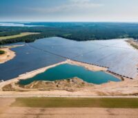 Luftaufnahme eines großen PV-Parks mit angrenzendem See einer Kiesgrube.