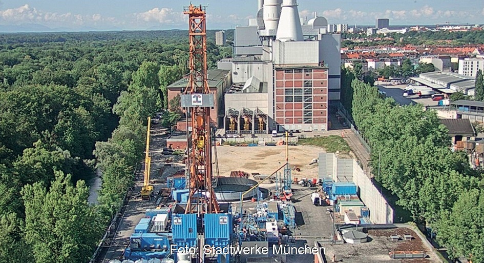 In der Mitte im Vordergrund ein oranger Bohrturm für Tiefengeothermie, links Wald, im Hintergrund ein Kraftwerk