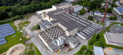 Luftaufnahme mit einem sanierungsbedürftiges Gewerbeareal mit Photovoltaik in der Nachbarschaft.