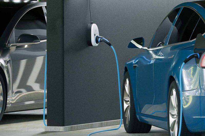 Zu sehen ist der go-e Charger und ein Kabel, der ein blaues E-Auto in einer Tiefgarage lädt.