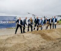 Mehrere Personen bei einem Spatenstich einer vorbereiteten Baustelle.
