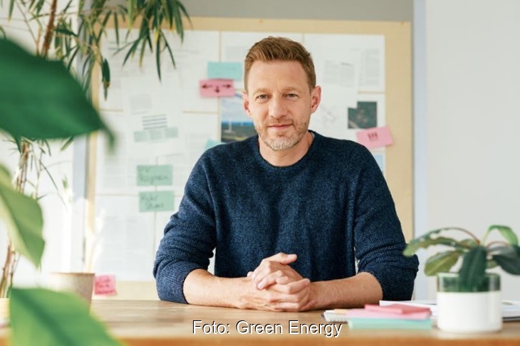 Nils Müller sitzt an einem Holzschreibtisch in einem Büro.