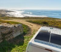 Ein Caravan mit Solarzellen an einer Küstenlandschaft mit Meer.