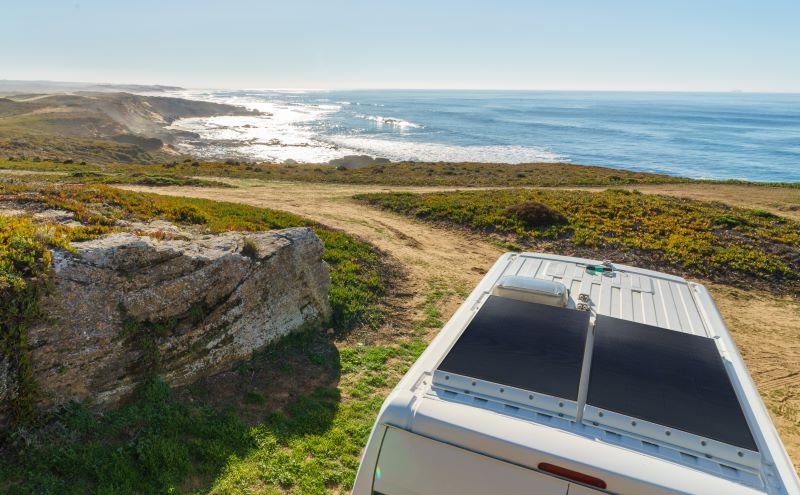 Ein Caravan mit Solarzellen an einer Küstenlandschaft mit Meer.