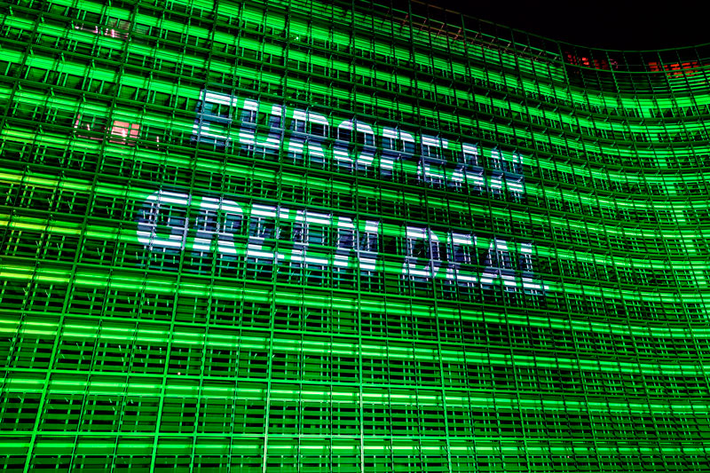 Fassade des Berlaymont-Gebäudes in Brüssel, nachts illuminiert mit der Schriftzug "Green New Deal"