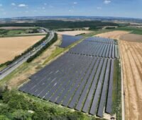 Luftbild eines Freiflächensolarparks an einer Autobahn.