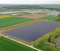 Luftbild eines Solarparks neben Wiesen und Äckern.