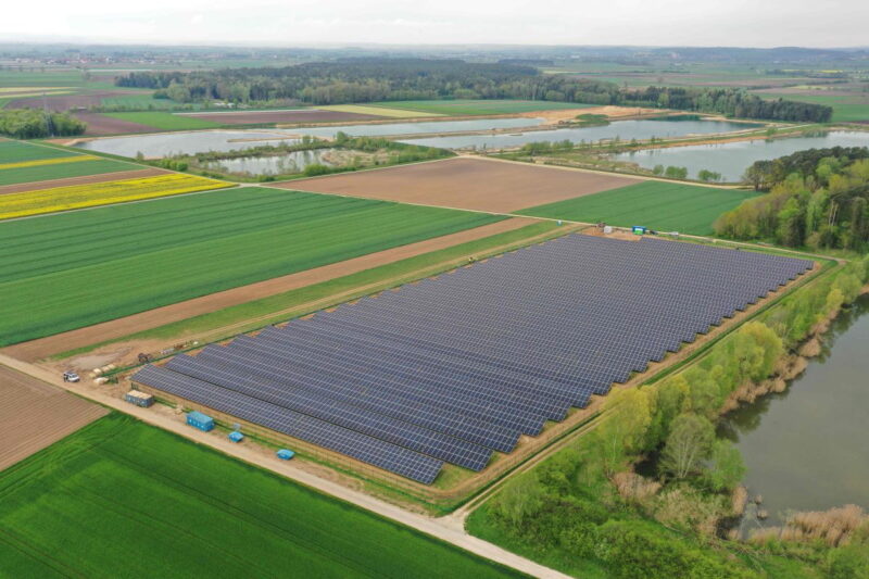 Luftbild eines Solarparks neben Wiesen und Äckern.