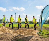 Fünf Männer mit gelben Westen und Spaten - Baustart für Photovoltaik-Projekt von greentech.