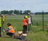 Zu sehen sind Forschenden, die eine Klimastation im Solarpark Weesow-Wilmersdorf erreichten, mit der sie die Auswirkung der Photovoltaik-Module auf die Austrocknung des Bodens untersuchen wollen.