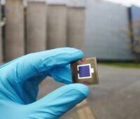 Zu sehen ist eine Hand in Handschuhen, die eine Perowskit-Solarzellen hält. Die Perowskit-Solarzellenforschung verfügt nun über eine Datenbank.