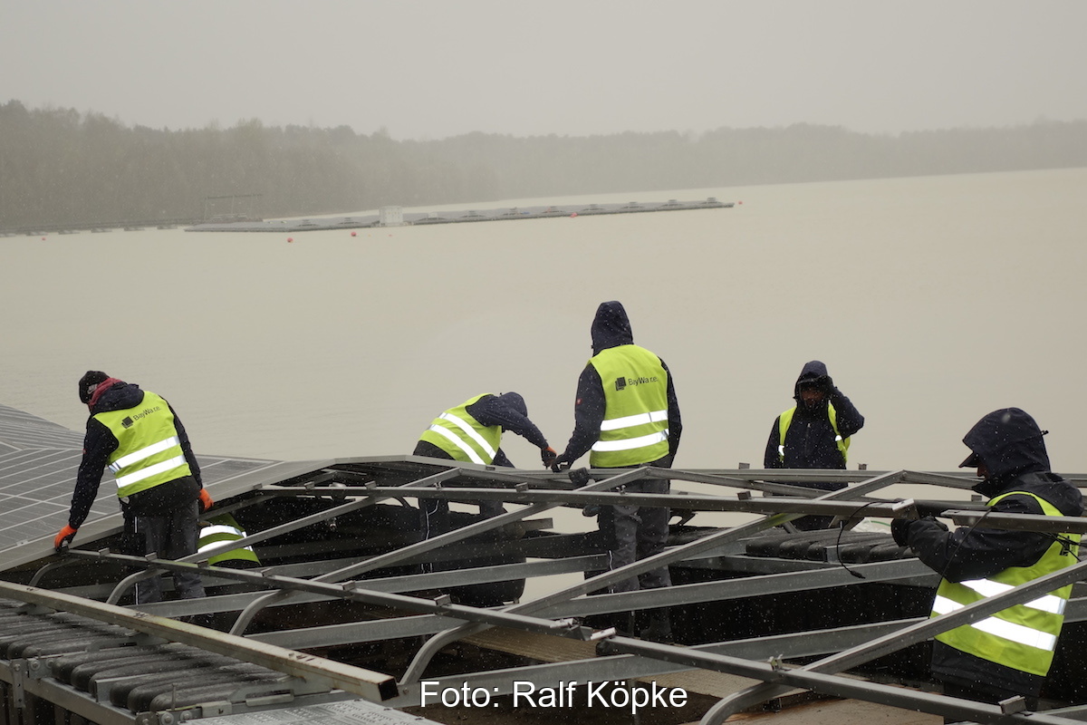Installateure bei der Arbeit: Sie schrauben Photovoltaik-Module auf die schwimmende Pontons für eine Floating-PV-Anlage