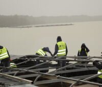 Installateure bei der Arbeit: Sie schrauben Photovoltaik-Module auf die schwimmende Pontons für eine Floating-PV-Anlage