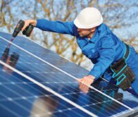 Handwerker montiert Photovoltaik-Module auf einem Schrägdach.
