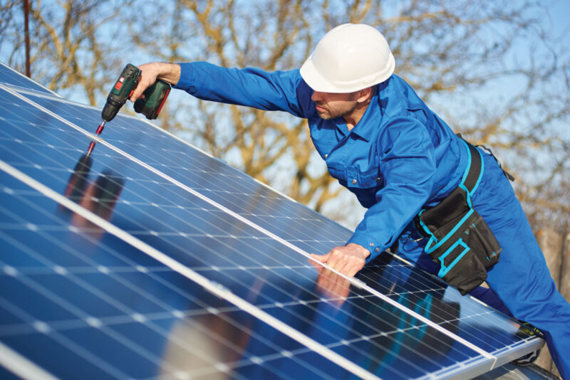 Handwerker montiert Photovoltaik-Module auf einem Schrägdach.