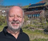 Hans-Josef Fell vor einem Haus mit Photovoltaik auf dem Dach. Eine Analyse zeigt: Erneuerbare erobern Weltenergiemärkte.
