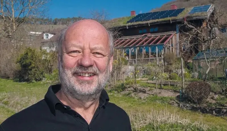 Hans-Josef Fell vor einem Haus mit Photovoltaik auf dem Dach. Eine Analyse zeigt: Erneuerbare erobern Weltenergiemärkte.