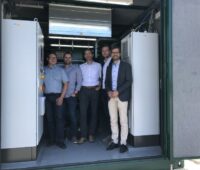 Fünf Männer stehen in einem Container für ein Wasserstoff-BHKW
