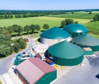 Luftbild von Bauernhof mit grünen Biogas-Fermentern.