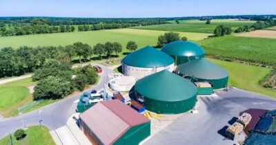 Luftbild von Bauernhof mit grünen Biogas-Fermentern.