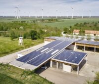Gutshof in Österreich mit PV-Dächern und Windpark im Hinterland.