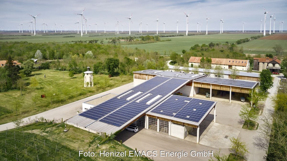 Gutshof in Österreich mit PV-Dächern und Windpark im Hinterland.