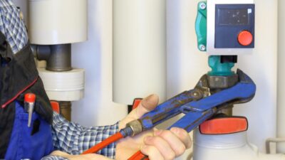 Hände mit Rohrzange und Heizungspumpe - Tausch alter Heiztechnik