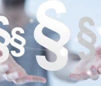 Im Bild zwei Hände mit mehreren Paragrafen als Symbol für die Stromsteuerrechts-Novelle.