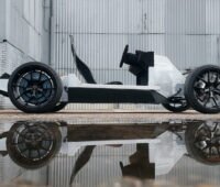 Zu sehen ist ein Kart-ähnliches Fahrzeug in einer Industriebrache mit Spiegelung im Wasser im Vordergrund.