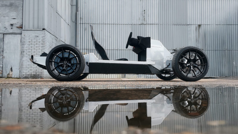 Zu sehen ist ein Kart-ähnliches Fahrzeug in einer Industriebrache mit Spiegelung im Wasser im Vordergrund.