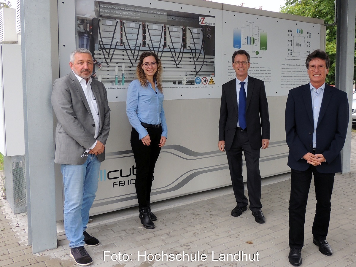 Zu sehen sind die Projektverantwortlichen vor einer Redox-Flow-Batterie, einem Teil der geplanten Hybrid-Energiespeicher.