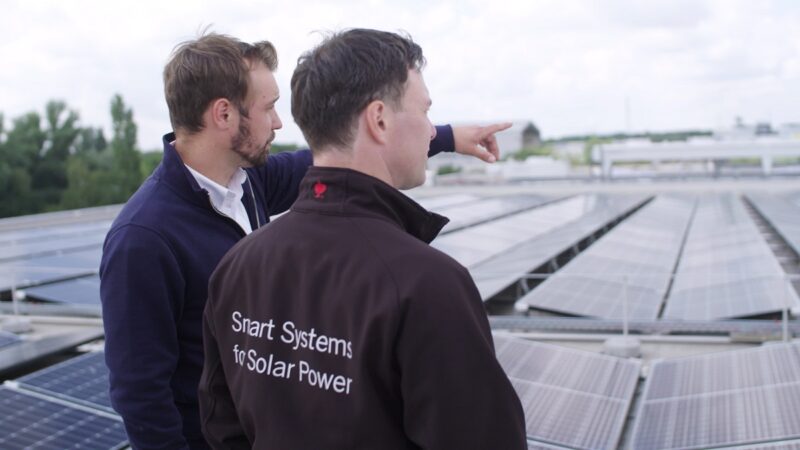Zu sehen sind zwei Menschen auf einem Hallendach mit Photovoltaik als Sinnbild für die Abteilung Commercial Energy Systems.