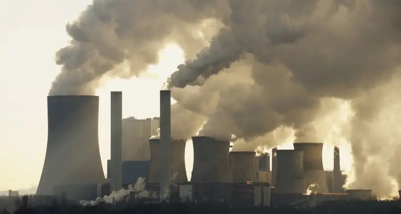 Zu sehen sind rauchende Schlote eines Braunkohlekraftwerks. Der IEA-Kohlebericht 2021 mahnt die Politik zu raschen Maßnahmen zur Reduzierung der Kohleverstromung.