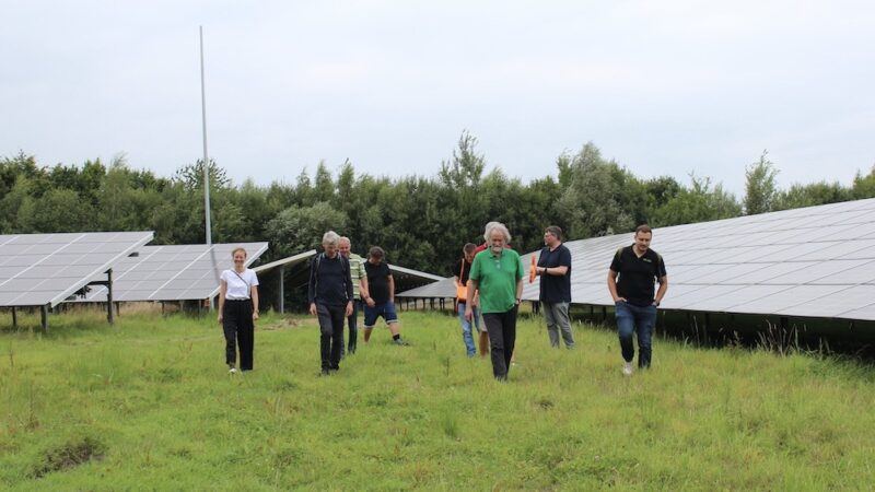 Personen, die für Bürgerenergie stehen, posieren vor Freiflächenparks.