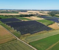 Solarpark aus der Vogelperspektive zwischen landwirtschaftlichen Flächen gelegen.