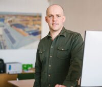 Poraitfoto von Dr. Johannes Weniger, stehend an einem Computerarbeitsplatz.