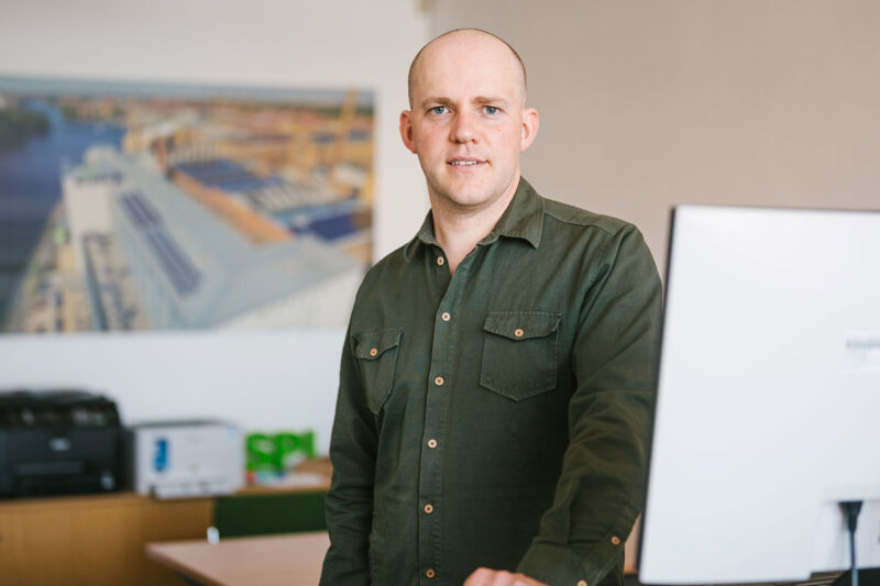 Poraitfoto von Dr. Johannes Weniger, stehend an einem Computerarbeitsplatz.