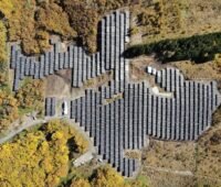 Luftbild von Photovoltaik-Anlage in herbstlichem Wald.