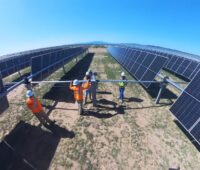 Weitwinkelaufnahme zeigt Bau an einem Freiflächensolarpark in trockener Landschaft.